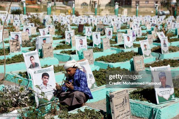 Man recites prayers on the grave of his relative killed during the country's war since it began in 2015, at a cemetery on December 24, 2023 in...