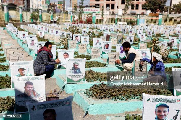 People recite prayers on the graves of their relatives killed during the country's war since it began in 2015, at a cemetery on December 24, 2023 in...