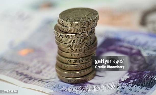 British one pound coins sit stacked on top of a 20 pound note in this arranged photograph taken in London, U.K., on Thursday, Nov. 14, 2013. The Bank...