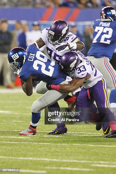 Running Back Michael Cox of the New York Giants is stopped by Defensive Tackle Sharrif Floyd and Safety Jamarca Sanford of the Minnesota Vikings at...