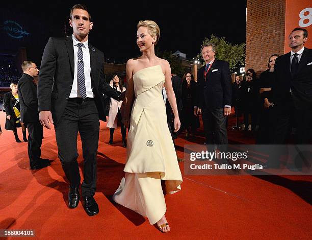 Actress Jennifer Lawrence is lead by a bodyguard during the 'The Hunger Games: Catching Fire' Premiere during The 8th Rome Film Festival at...