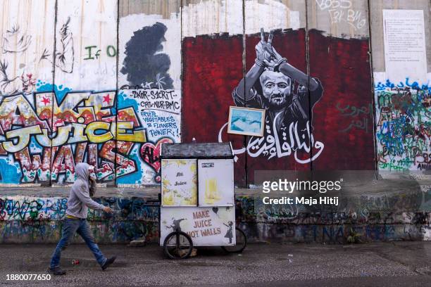 Palestinian man pass the graffiti showing Marwan Barghouti, a Palestinian imprisoned politician on December 24, 2023 in Bethlehem, West Bank. Last...