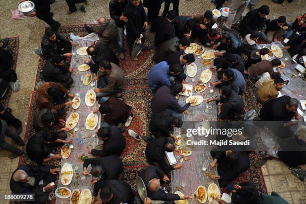 Iranians eat food during the Ashura mourning feast November 14, 2013 in the village of Bagh Malek ,480 Km south of Tehran, Iran. The Ashura day...