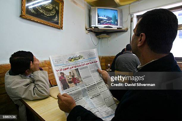 Palestinian men catch up on the news as al-Jazeera television broadcasts on the war in Iraq in the el-Arabe coffee shop March 27, 2003 in the West...