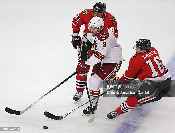 Keith Yandle of the Phoenix Coyotes skates between Marian Hossa and Marcus Kruger of the Chicago Blackhawks at the United Center on November 14, 2013...