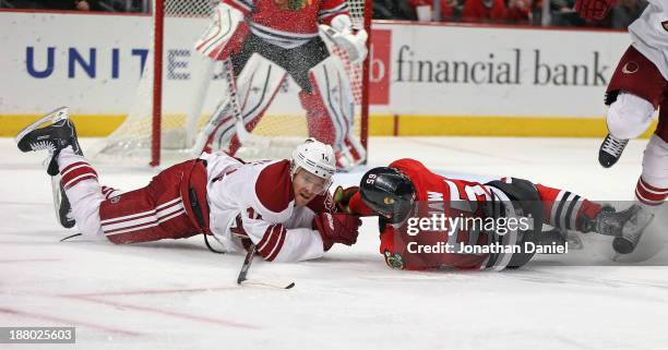 Andrew Shaw of the Chicago Blackhawks and Jeff Halpern of the Phoenix Coyotes hit the ice after colliding at the United Center on November 14, 2013...