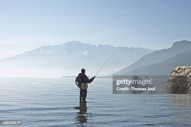 man fly fishing in lake como - fliegenfischen stock-fotos und bilder