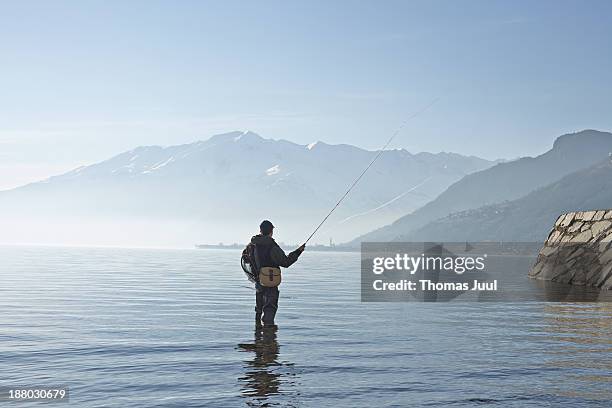 man fly fishing in lake como - fly fishing stockfoto's en -beelden