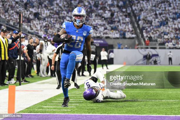 Jahmyr Gibbs of the Detroit Lions scores a rushing touchdown against Mekhi Blackmon of the Minnesota Vikings during the second quarter at U.S. Bank...
