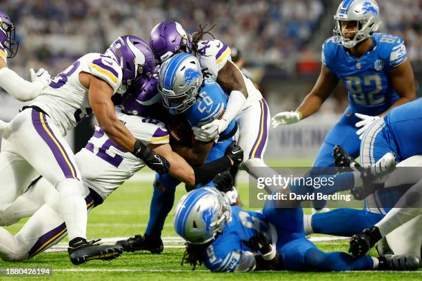 Jahmyr Gibbs of the Detroit Lions is tackled by Harrison Smith and Josh Metellus of the Minnesota Vikings during the third quarter at U.S. Bank...