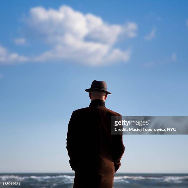 man in hat staring at the sea - coat imagens e fotografias de stock