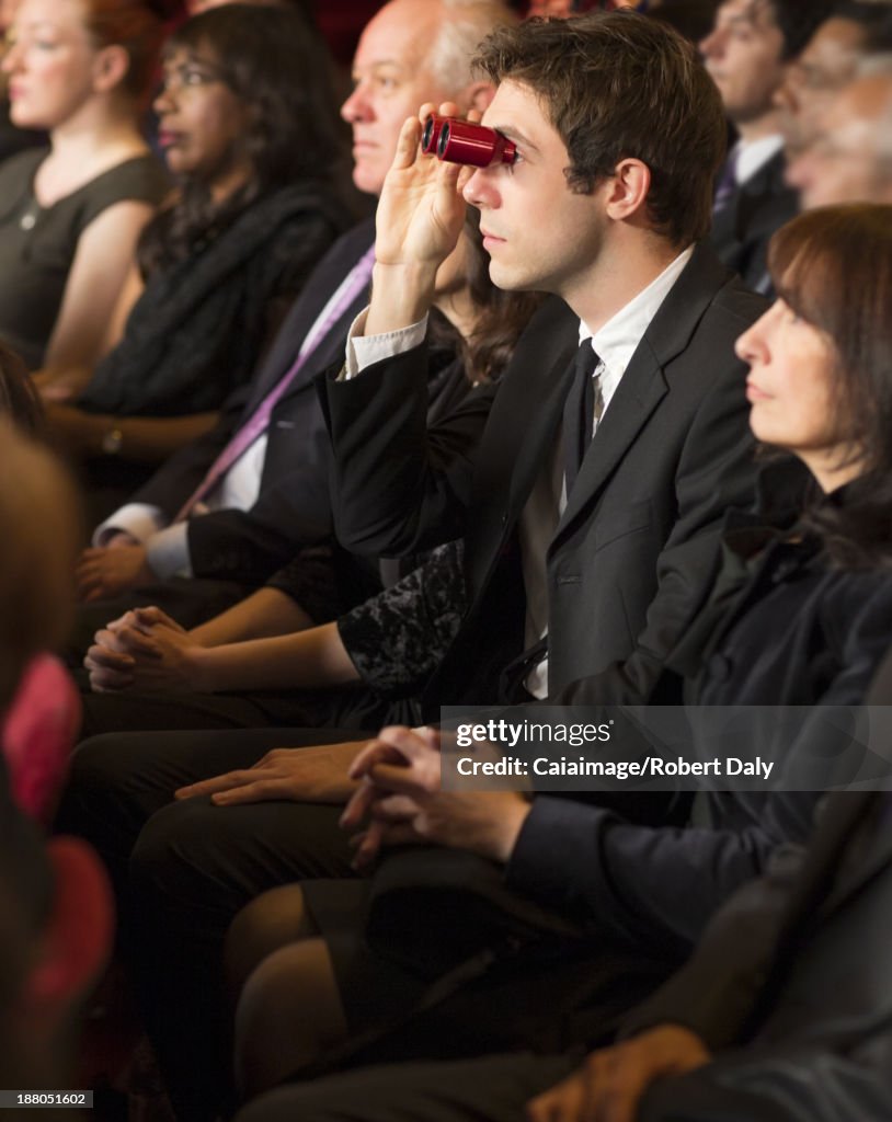 Man using opera glasses in theater audience