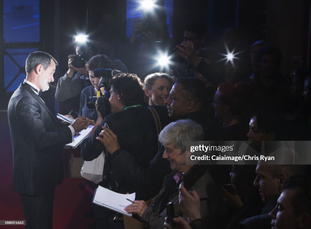 Celebrity signing autographs on red carpet