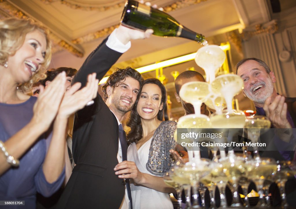 Well dressed couple pouring champagne pyramid