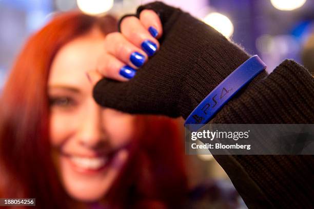 Meredith Molinari, PlayStation Network presenter, shows off a wristband bearing the logo of the Sony PlayStation 4 console during its midnight launch...