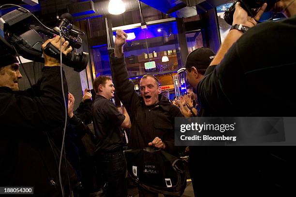 Wade Smith pumps his fist after purchasing the first Sony PlayStation 4 console of the night during its midnight launch event in San Francisco,...
