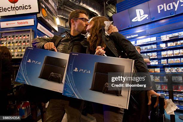 Jordan Smith, left, and Kayla Brittingham, share a kiss after purchasing the Sony PlayStation 4 console during its midnight launch event in San...