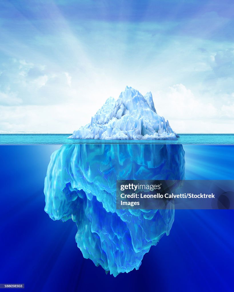 Solitary iceberg in the sea with a soft cloudy sky in the background.