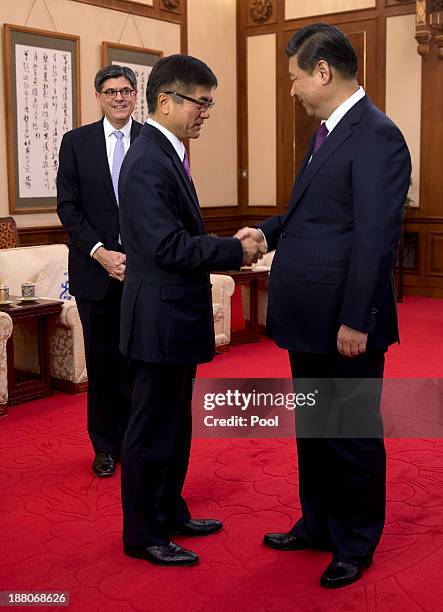 Treasury Secretary Jack Lew looks toward Chinese President Xi Jinping who shakes hands with U.S Ambassador to China Gary Locke before their meeting...