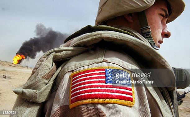 Army Specialist Chad Morton, of George West, Texa,s stands next to a burning oil well at the Rumayla oil fields March 27, 2003 in Rumayla, Iraq....
