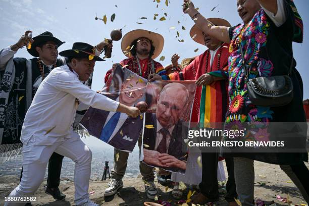 Peruvian shamans, equipped with coca leaves, swords, smoking ceramic pots, and incense, display posters of US President Joe Biden and Russia's...