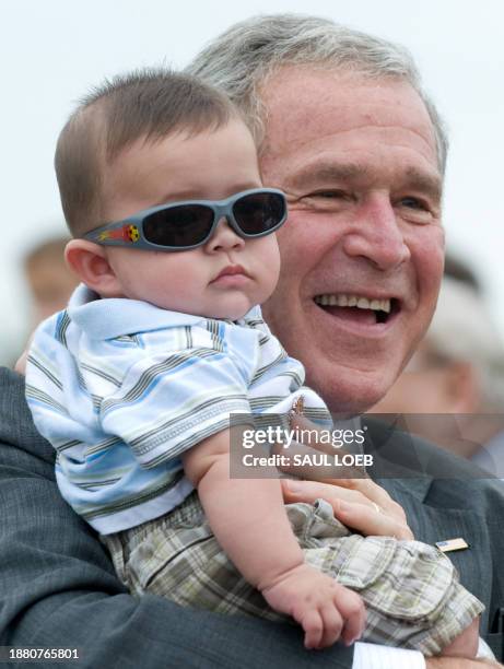 President George W. Bush holds five-month old Stanley Debshaw while greeting guests prior to departing on Air Force One from Greater Peoria Regional...