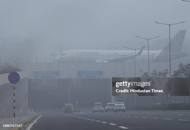 Passenger airline aircraft on the elevated dual eastern cross taxiway in heavy thick early morning fog at IGI T3 Terminal T on December 27, 2023 in...