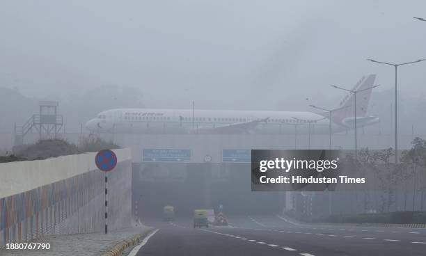 Passenger airline aircraft on the elevated dual eastern cross taxiway in heavy thick early morning fog at IGI T3 Terminal T on December 27, 2023 in...