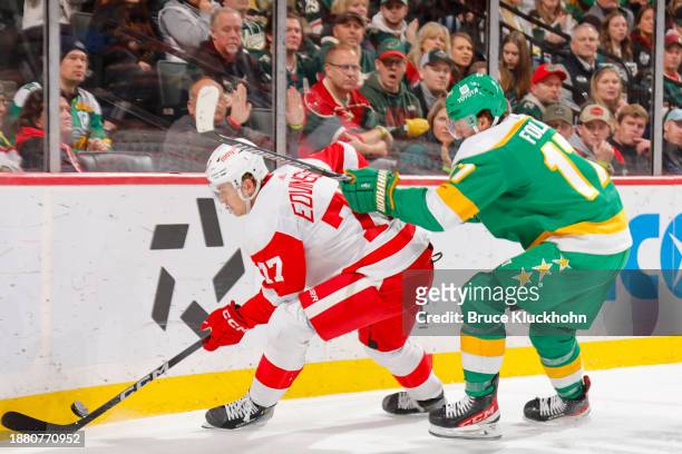 Simon Edvinsson of the Detroit Red Wings handles the puck with Marcus Foligno of the Minnesota Wild defending during the game at the Xcel Energy...