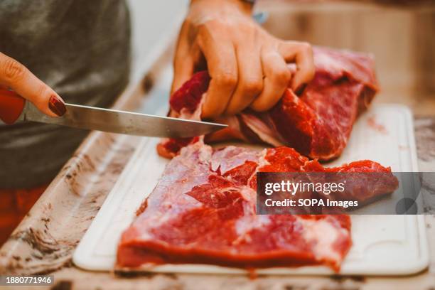 Cook is cuts up a lump of beef. Beef provides essential vitamins and minerals such as vitamin B12, zinc, selenium, iron, niacin, and vitamin B6.