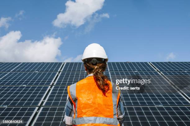 solarkraft-profi: rückansicht einer jungen ingenieurin im kraftwerk sun power - nachhaltiges wirtschaften stock-fotos und bilder