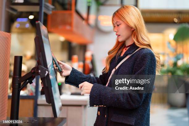 young asian female using electronic kiosk - the internet of things stock pictures, royalty-free photos & images