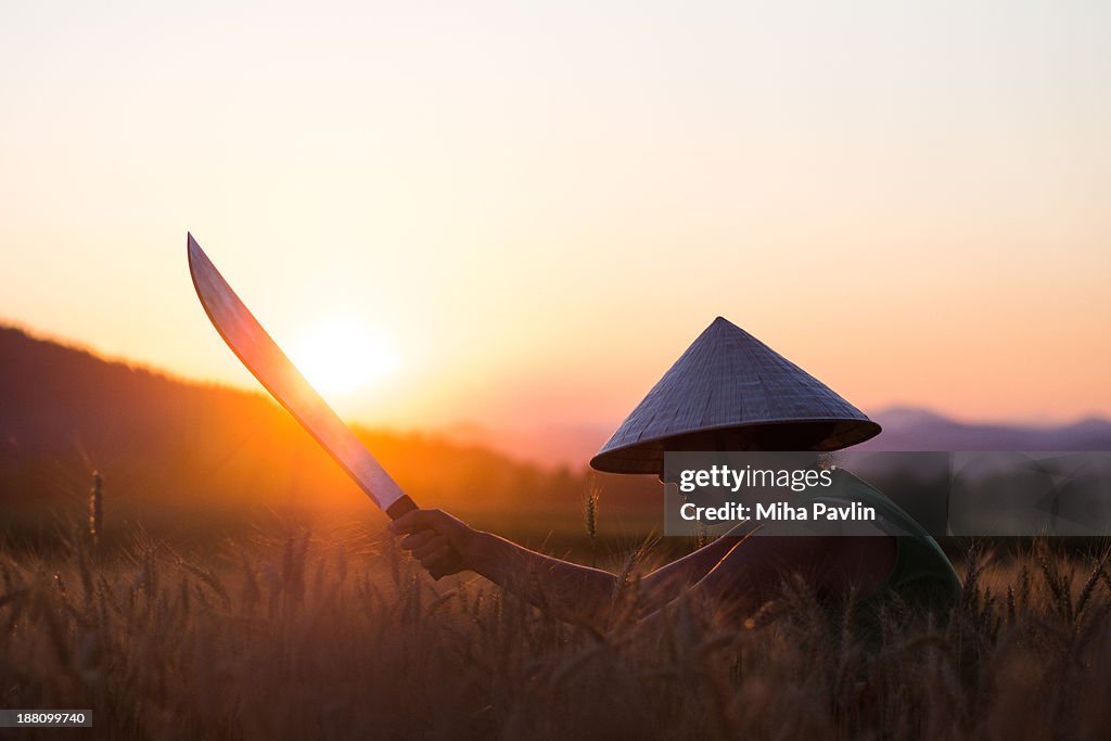 Woman with conical hat and machete at sunset