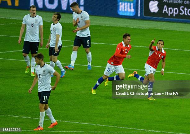 Alexis Sanchez of Chile celebrates scoring their first goal as Phil Jones, Leighton Baines, Gary Cahill and Jay Rodriguez of England looking dejected...