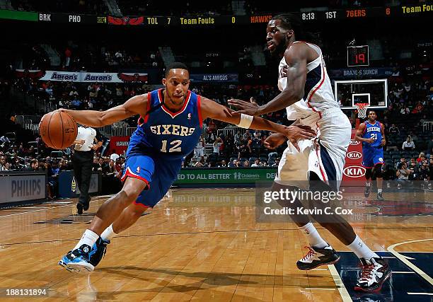 Evan Turner of the Philadelphia 76ers drives against DeMarre Carroll of the Atlanta Hawks at Philips Arena on November 15, 2013 in Atlanta, Georgia....