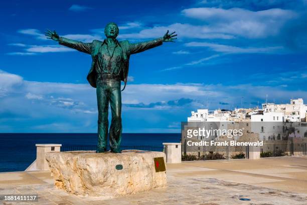 Statue of Domenico Modugno, the singer of the famous song Volare, houses of the small town in the distance.