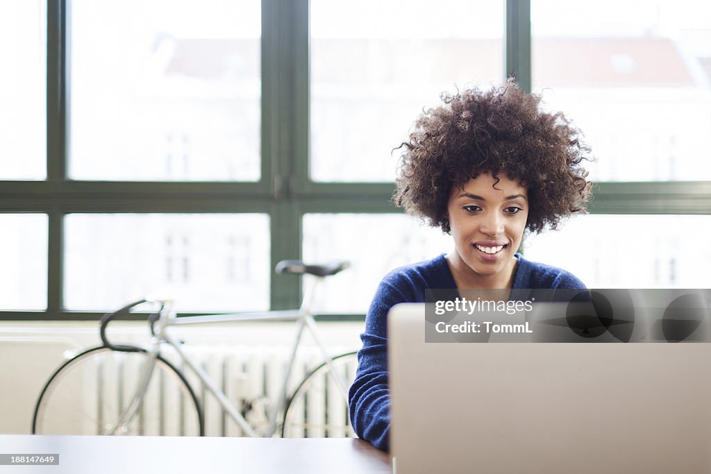 Jeune femme travaillant dans l'espace Loft derrière un ordinateur portable