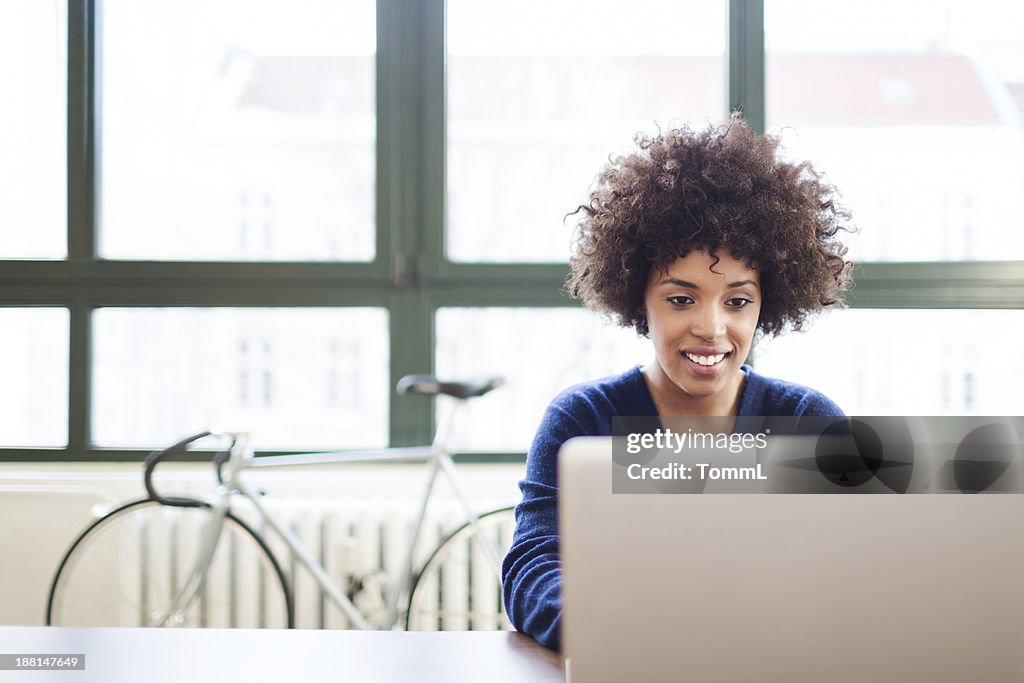 Young Woman Working in Loft Space Behind Laptop