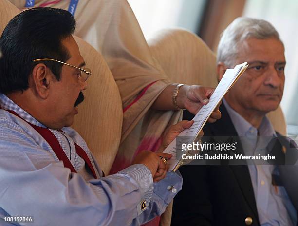 Sri Lankan President Mhainda Rajapaksa reads a document as Commonwealth Secretary General Kamalesh Sharma looks on the Heads of State meeting at...