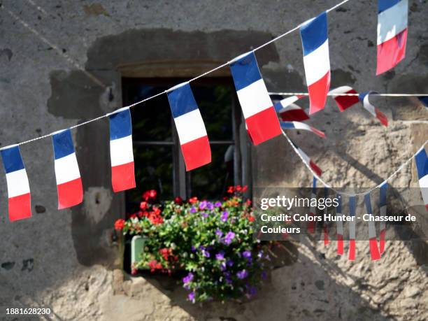 garlands of french flags in front of the flowered window in evian-les-bains, haute-savoie, france. no people. - bastille day stock pictures, royalty-free photos & images