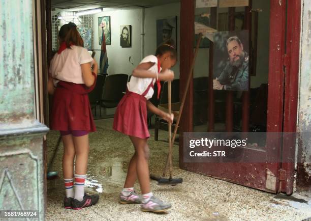 Schoolgirls clean the floor at a school in Havana near a portrait of President Fidel Castro on February 21, 2008. Interim president Raul Castro...