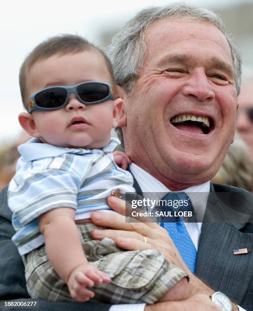 President George W. Bush holds 5-month old Stanley Debshaw while greeting guests prior to departing on Air Force One from Greater Peoria Regional...