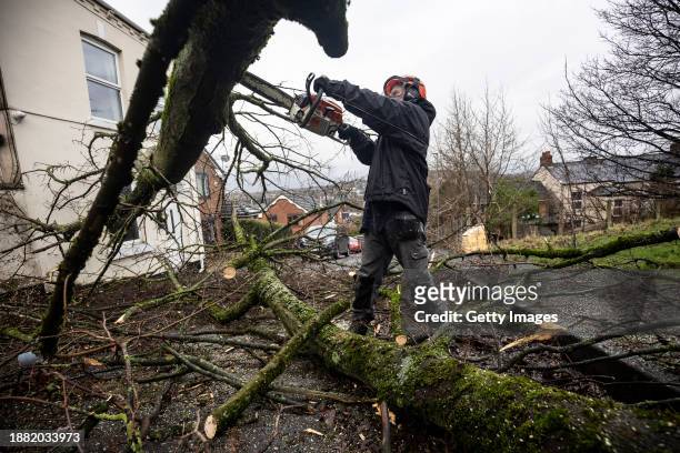 Tree surgeon removes a fallen tree following a tornado on December 28, 2023 in Stalybridge, England. Houses in the Tameside area of Greater...