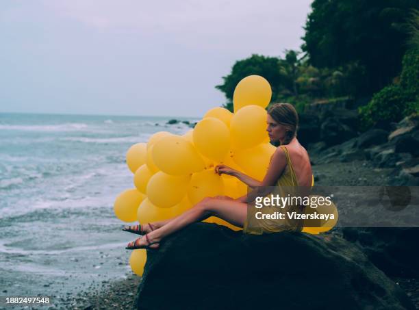 young woman walking with many balloons in sunset at the ocean beach - balloon woman party stock pictures, royalty-free photos & images