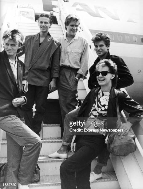 British pop group Duran Duran smile and laugh while posing on an airplane ramp before departing for Australia, Heathrow Airport, London, England,...