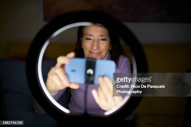 senior woman vlogger broadcasting on social media - selective focus imagens e fotografias de stock
