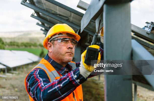 trabajador de la construcción experimentado: hombre mayor que construye una cerca de metal con taladro - hoja de aluminio fotografías e imágenes de stock