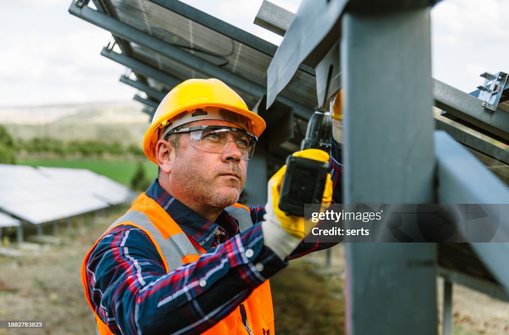Experienced Construction Worker: Elderly Man Building Metal Fence with Drill