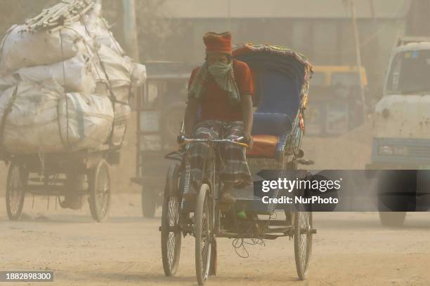 Rickshaw puller is riding on a dusty and heavily polluted road in Dhaka, Bangladesh, in December 2023.