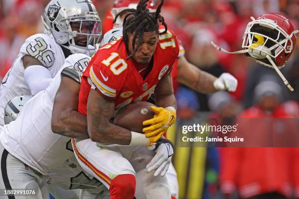 Isiah Pacheco of the Kansas City Chiefs loses his helmet as he's tackled by Divine Deablo of the Las Vegas Raiders during the third quarter at GEHA...